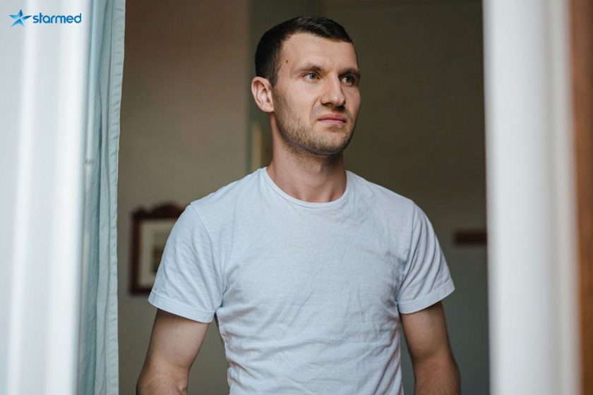 Мужчина стоит и смотрит в окно